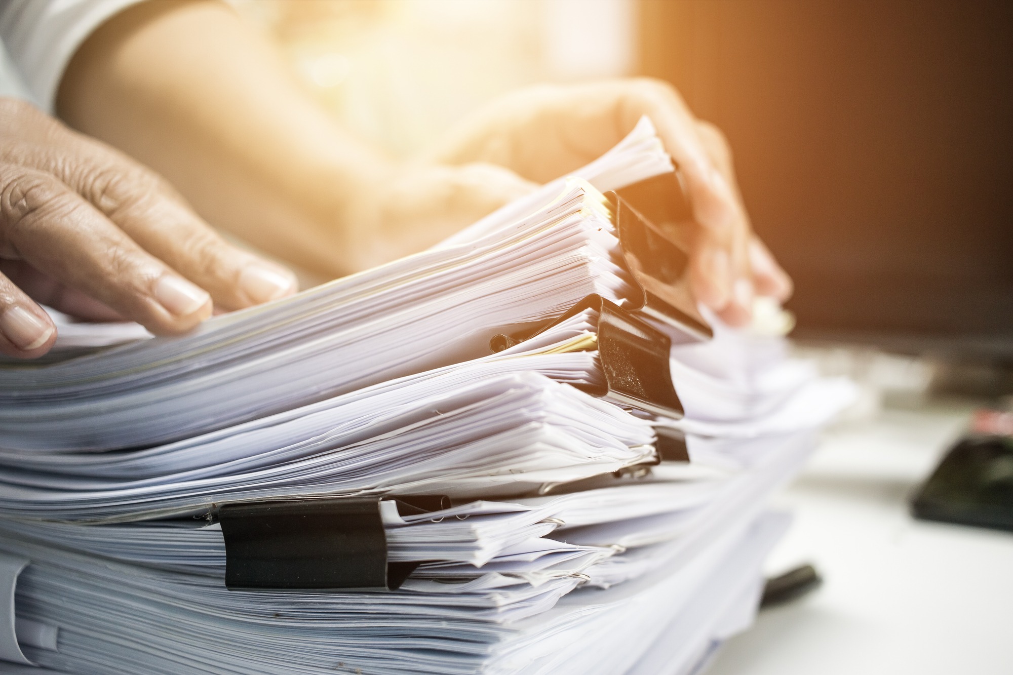 Businessman Hands Working In Stacks of Paper Files for Searching Information on Work Desk Office, Business Report Papers,Piles of Unfinished Documents Achieves With Clips Indoor,Business Concept